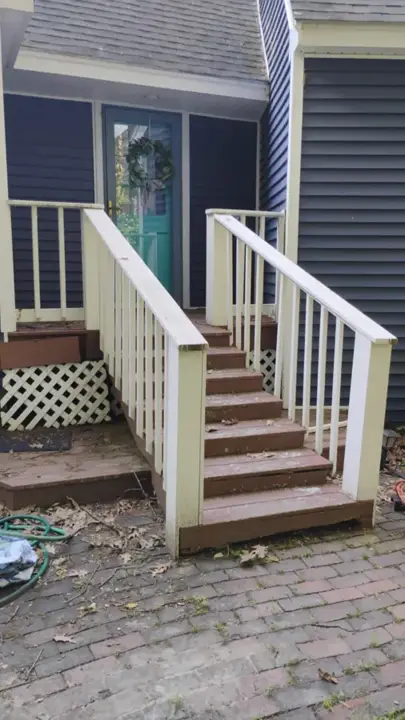 Weathered wooden entry steps and railings at a blue house before removal